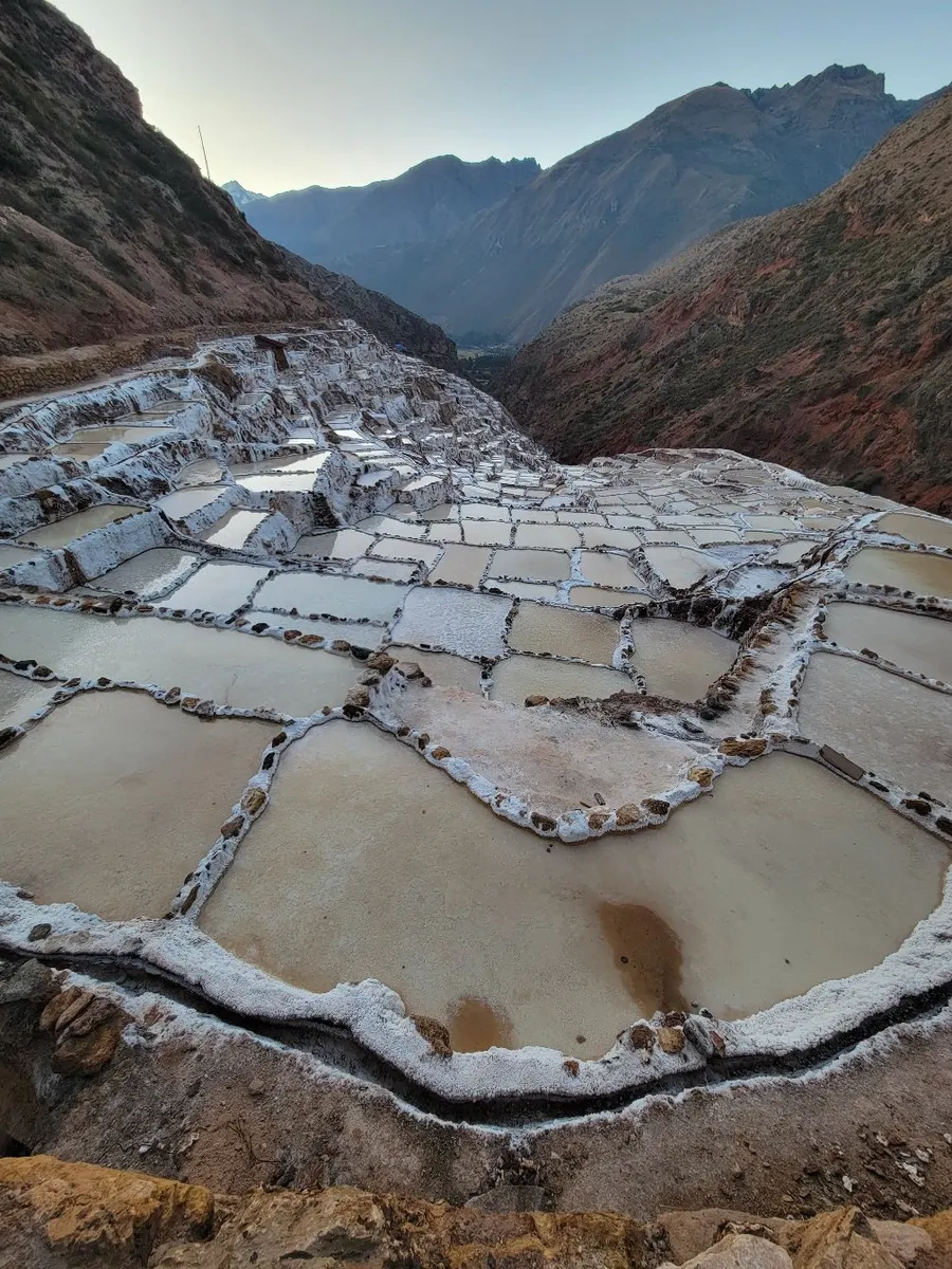 Terraced salt evaporation ponds descending a mountain valley